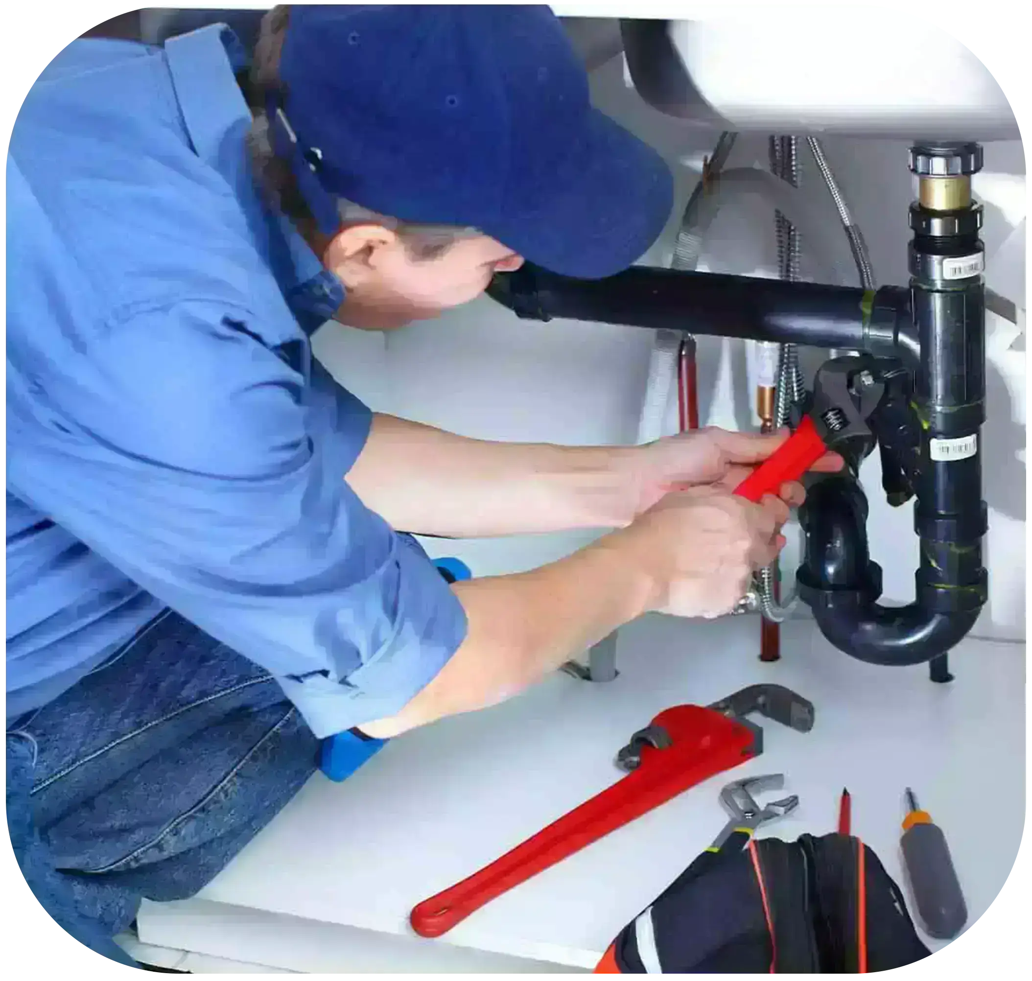 A technician in a blue shirt paired with blue jeans and a blue cap is repairing  a water pipe by using pliers.